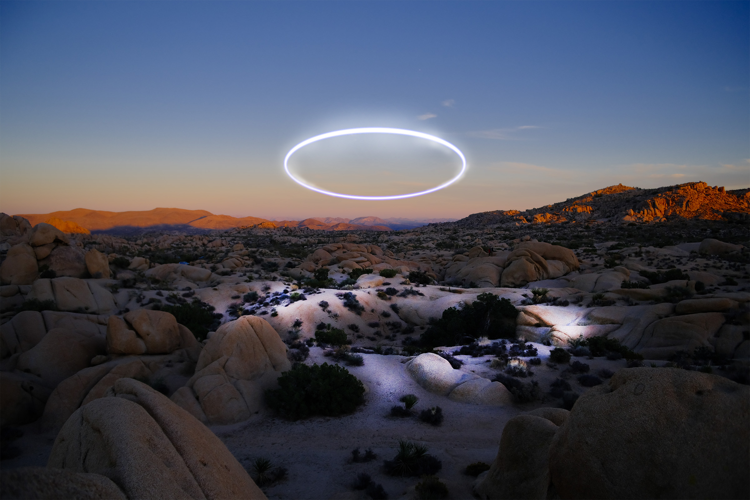 A luminous halo hovers above a desert landscape at dusk.